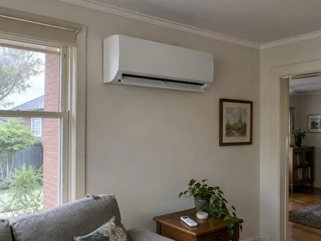 White split system mounted high on a beige living room wall with open louvre and a window beside it in Adelaide